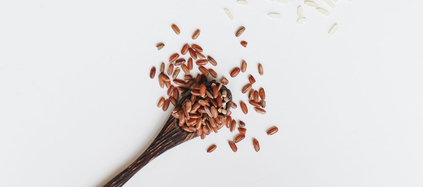 Cucharas de madera con granos de arroz sobre fondo claro