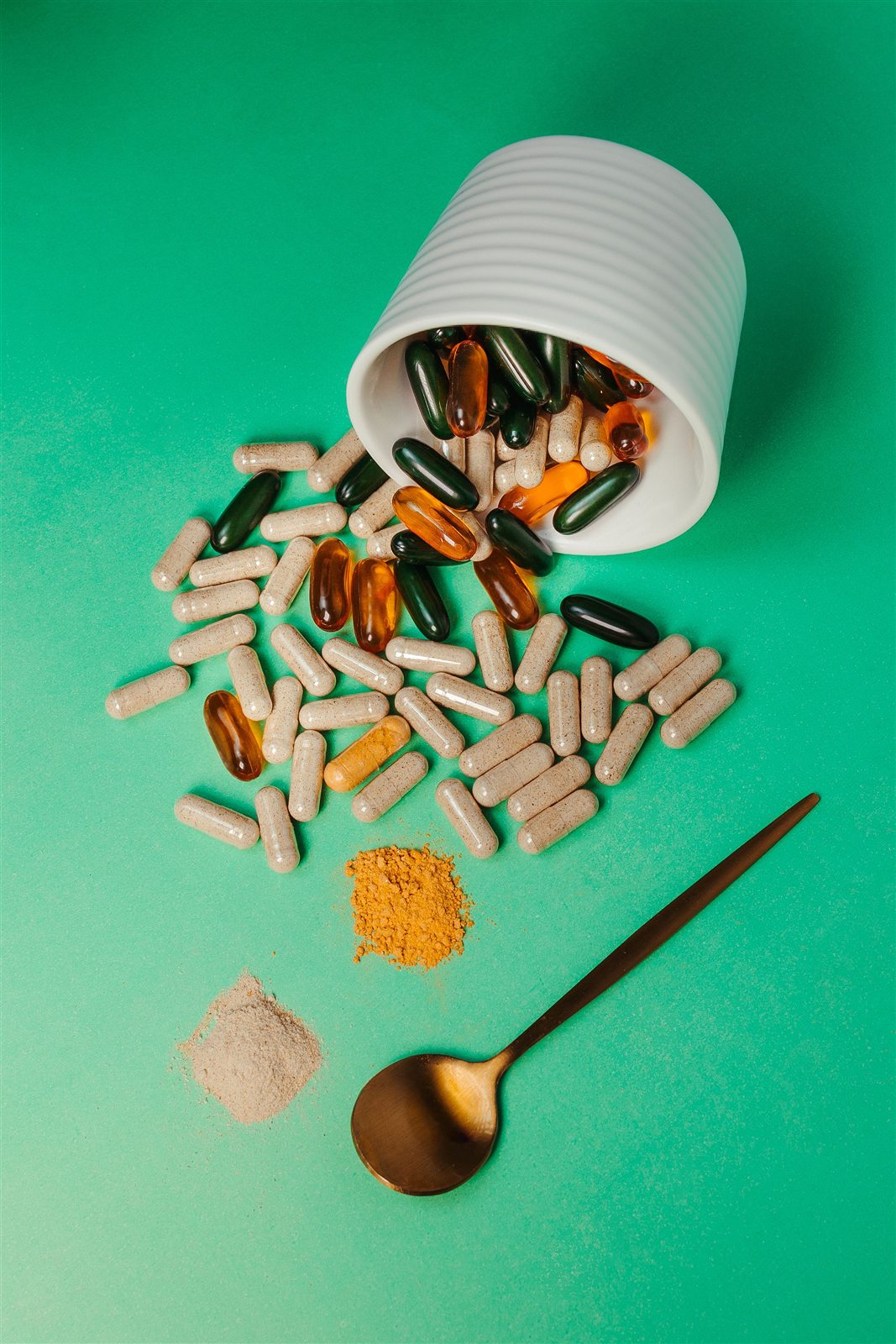 Cápsulas y extractos nutracéuticos sobre fondo verde